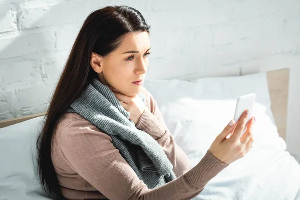 Atractiva mujer enferma que tiene consulta en línea con el médico en el teléfono inteligente - foto de stock