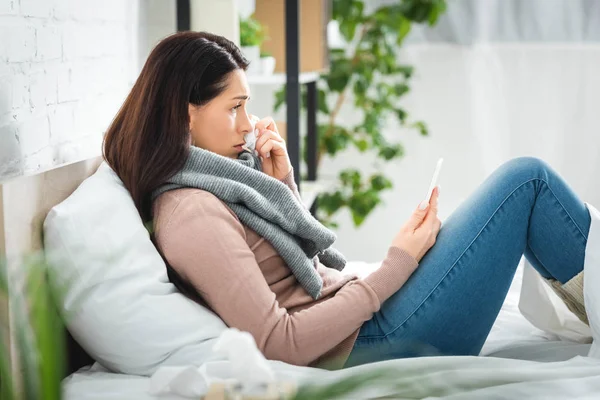 Atractiva mujer enferma con servilleta que tiene consulta en línea con el médico en el teléfono inteligente - foto de stock