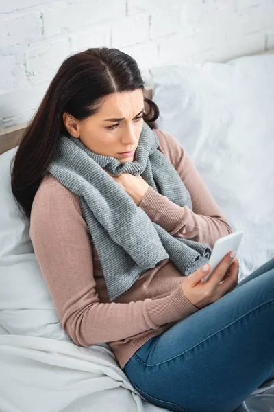 Больная женщина, имеющая онлайн консультации с врачом на смартфоне — стоковое фото