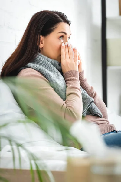 Femme malade en écharpe avec nez qui coule tenant la serviette à la maison — Photo de stock