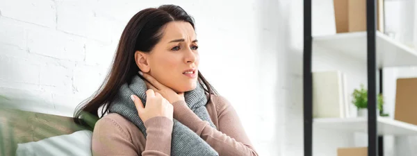 Panoramic shot of beautiful sick woman in scarf having sore throat at home — Stock Photo