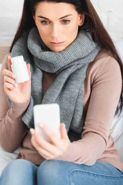 Beautiful ill woman with pills having online consultation with doctor on smartphone — Stock Photo