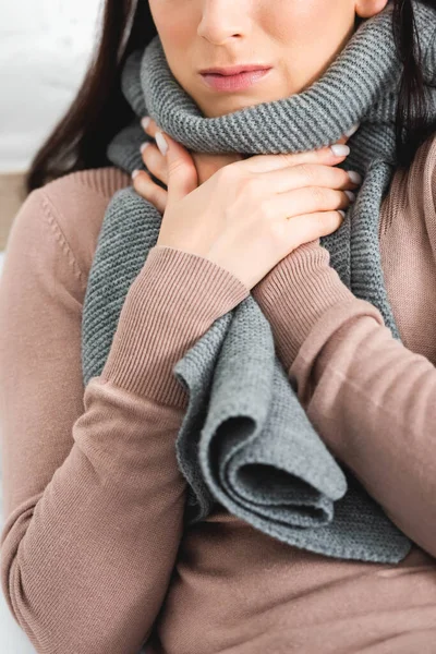 Vue recadrée de la femme malade en écharpe ayant mal à la gorge à la maison — Photo de stock