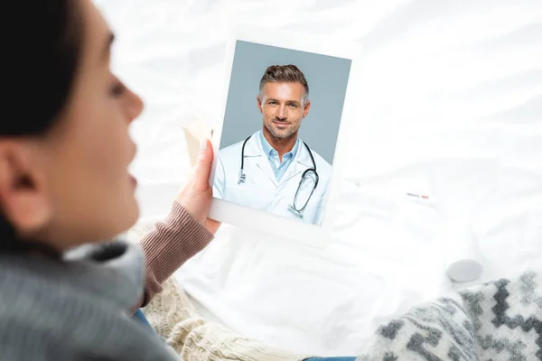 Mujer enferma que tiene consulta en línea con el médico masculino en la tableta digital - foto de stock