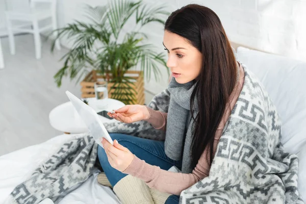 Hermosa mujer enferma con fiebre teniendo consulta en línea con el médico en la tableta digital - foto de stock