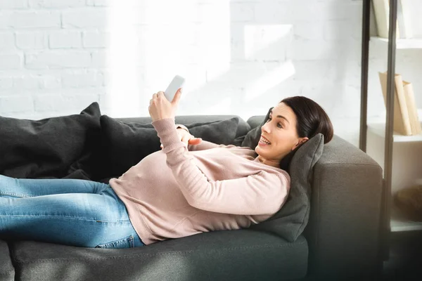 Souriant femme enceinte ayant une consultation en ligne avec le médecin sur smartphone — Photo de stock