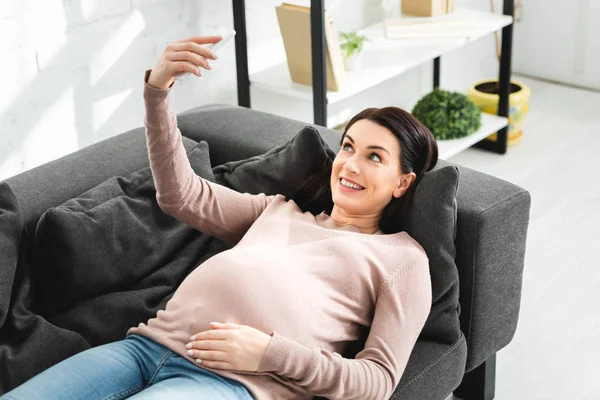 Cheerful pregnant woman having online consultation with doctor on smartphone — Stock Photo