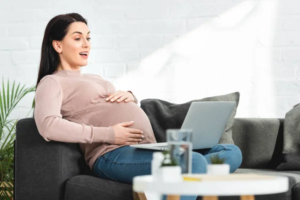 Mulher grávida atraente ter consulta on-line com o médico no laptop em casa — Fotografia de Stock