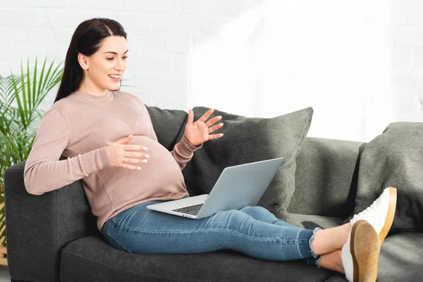 Eccitata donna incinta avendo consultazione online con il medico sul computer portatile a casa — Foto stock