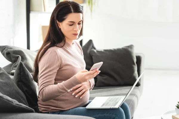 Femme enceinte ayant une consultation en ligne avec un médecin sur ordinateur portable et smartphone — Photo de stock