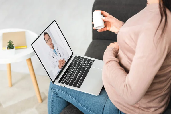 Cropped view of pregnant girl holding pills while having online consultation with doctor on laptop — Stock Photo