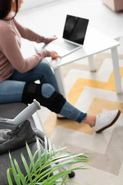 Foco seletivo da mulher com a perna quebrada ter consulta on-line com o médico no laptop em casa — Fotografia de Stock