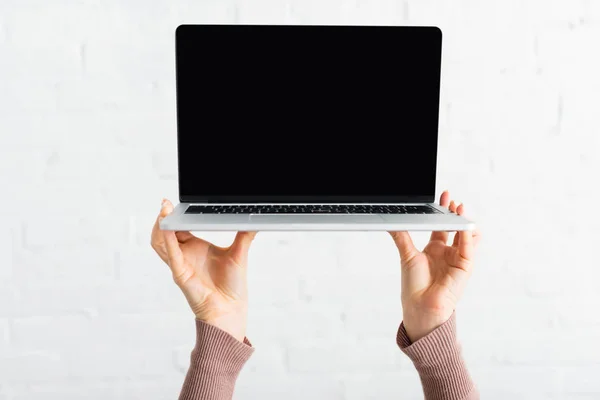 Cropped view of woman holding laptop with blank screen — Stock Photo