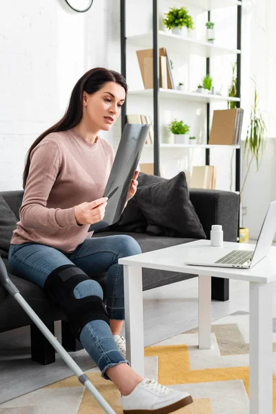 Woman showing x-ray of leg on online consultation with doctor on laptop — Stock Photo