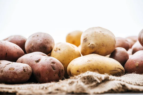 Messa a fuoco selettiva di patate crude biologiche su sacco rustico marrone isolato su bianco — Foto stock