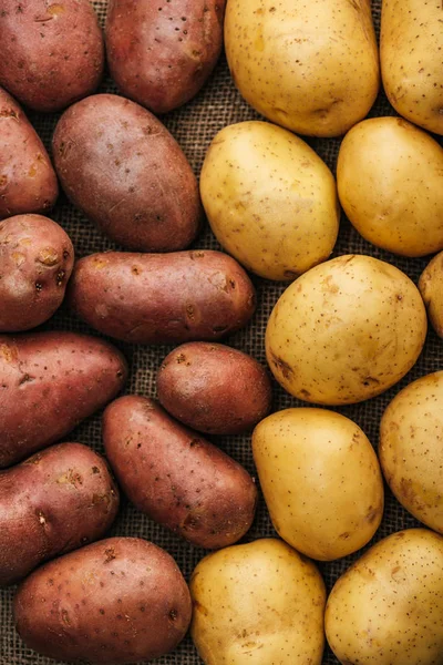 Vista superior de batatas cruas orgânicas em pano de saco rústico marrom — Fotografia de Stock