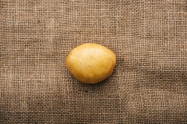 Вид зверху на органічну сиру картоплю на коричневому сільському мішковині — стокове фото