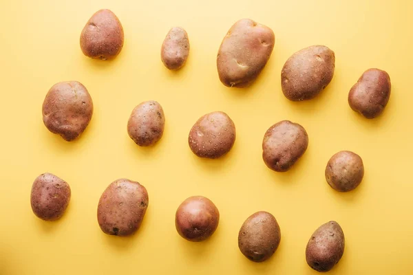 Vista superior de batatas frescas inteiras cruas no fundo amarelo — Fotografia de Stock