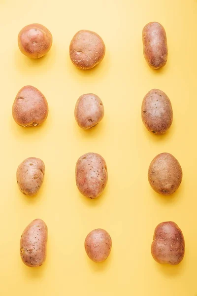 Vista superior de papas frescas enteras crudas sobre fondo amarillo - foto de stock