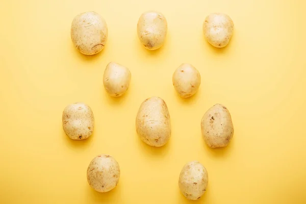 Top view of raw whole fresh potatoes on yellow background — Stock Photo
