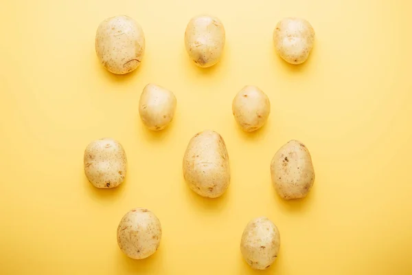 Vista superior de papas frescas enteras crudas sobre fondo amarillo - foto de stock