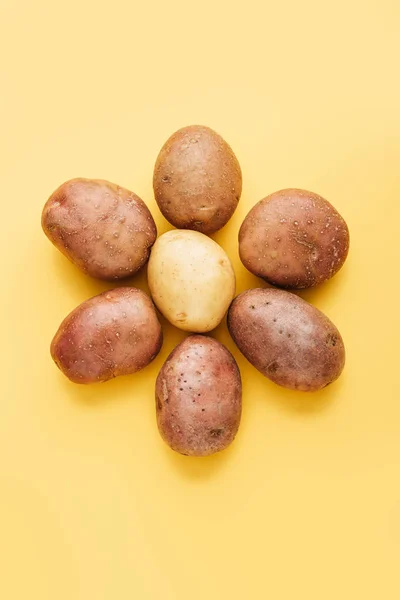 Vista superior de batatas frescas inteiras cruas dispostas em flor sobre fundo amarelo — Fotografia de Stock
