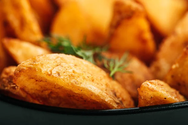 Close up view of delicious golden potato wedges with dill in bowl — Stock Photo