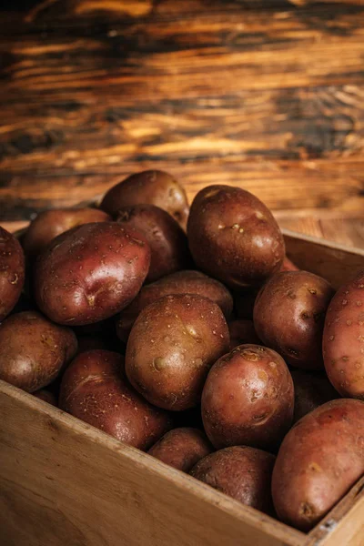 Close up view of fresh ripe potatoes in box on wooden background — Stock Photo