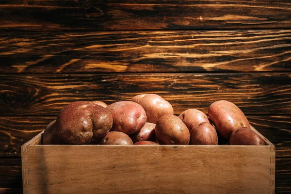 Batatas maduras frescas em caixa no fundo de madeira — Fotografia de Stock