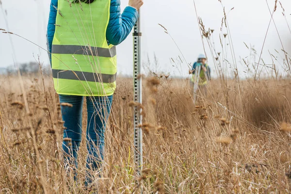 Vista ritagliata degli ispettori con righello di rilevamento e livello digitale nel campo — Foto stock