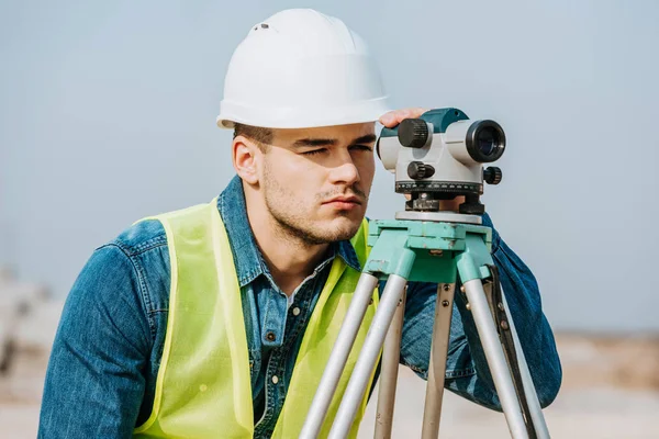 Сервеєр у куртці Hardhat та високої видимості з використанням цифрового рівня — стокове фото