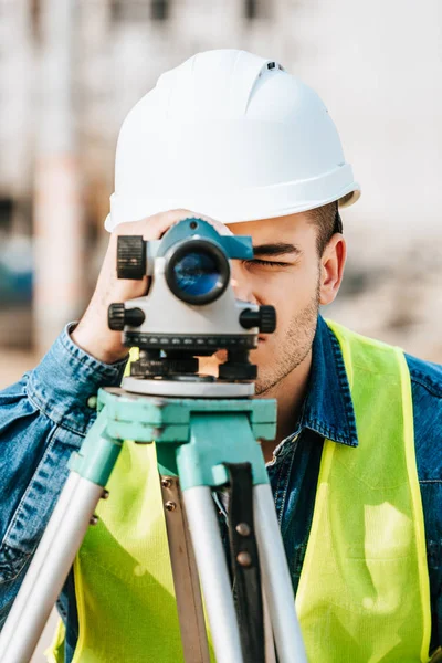 Сервеєр у куртці Hardhat та високої видимості, який дивиться на весь цифровий рівень — стокове фото