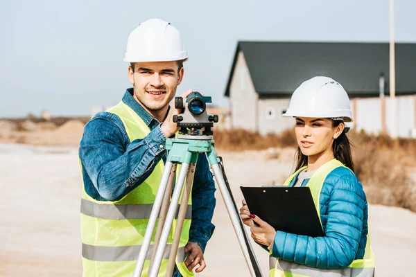 Surveyors with digital level and clipboard looking away — Stock Photo