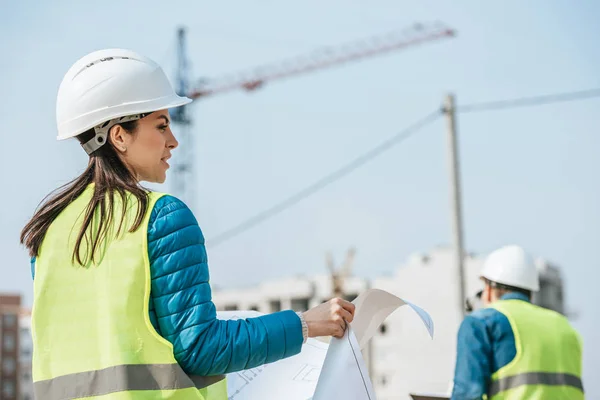 Selective focus of surveyors with blueprint on construction site — Stock Photo