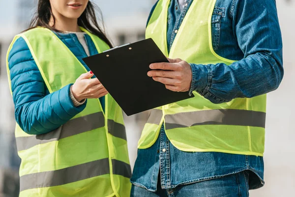 Cropped view of Surveyors in high visibility jackets holding clipboard — Stock Photo