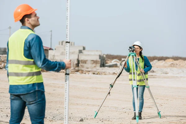 Enfoque selectivo de topógrafos utilizando nivel digital y regla en el sitio de construcción - foto de stock