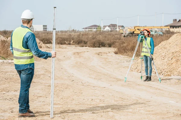 Surveyors with digital level and survey ruler working on dirt road — Stock Photo