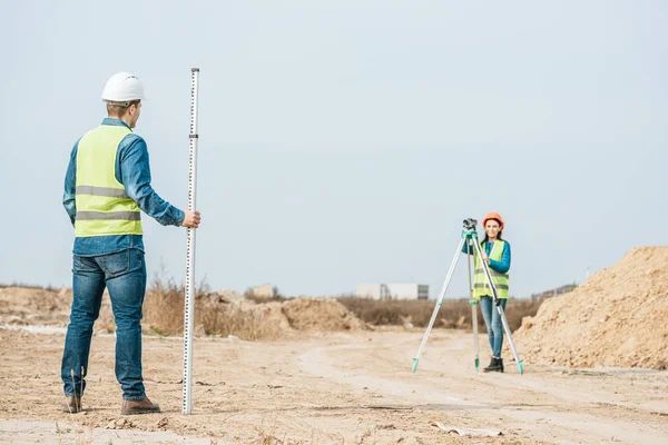 Surveyors using digital level and survey ruler on dirt road — Stock Photo