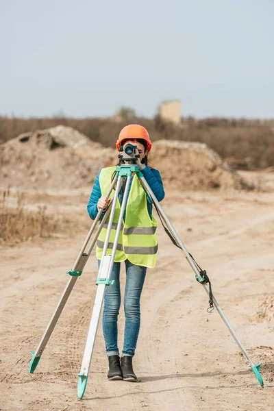 Inspetor feminino usando nível digital na estrada de terra — Fotografia de Stock