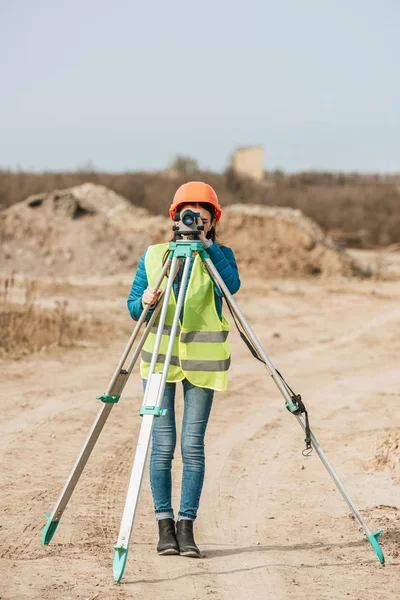Female surveyor using digital level on dirt road — Stock Photo