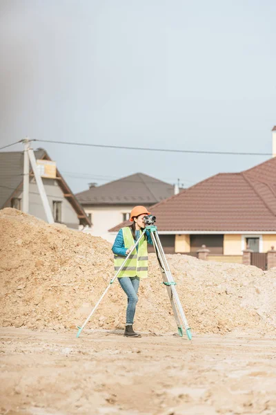 Vermessungsingenieurin mit digitalem Pegel auf Feldweg mit Sandhügeln — Stockfoto