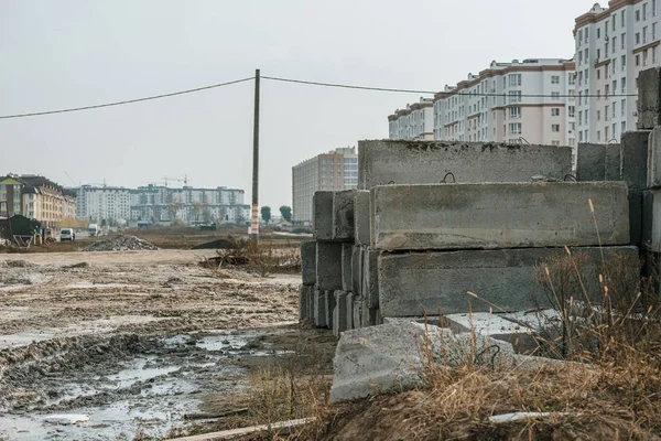 Blocchi di cemento su strada sterrata e cantiere sullo sfondo — Foto stock