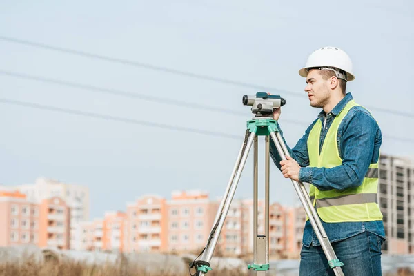 Vista laterale del geometra con livello digitale che distoglie lo sguardo — Foto stock