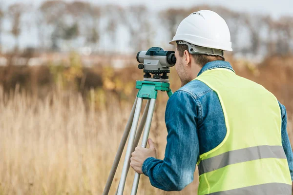 Surveyor looking through digital level in field — Stock Photo