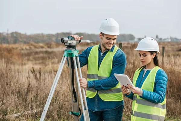 Surveyors working with digital level and tablet in field — Stock Photo