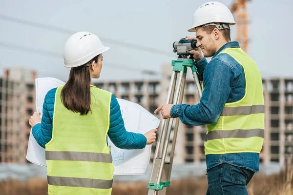 Surveyors working with blueprint and digital level — Stock Photo