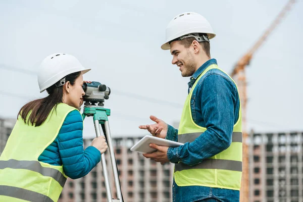 Vermessungsingenieure mit Tablet und digitalem Pegel auf Baustelle — Stockfoto