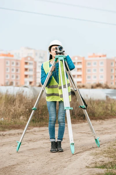Encuestadora femenina midiendo tierra con nivel digital - foto de stock