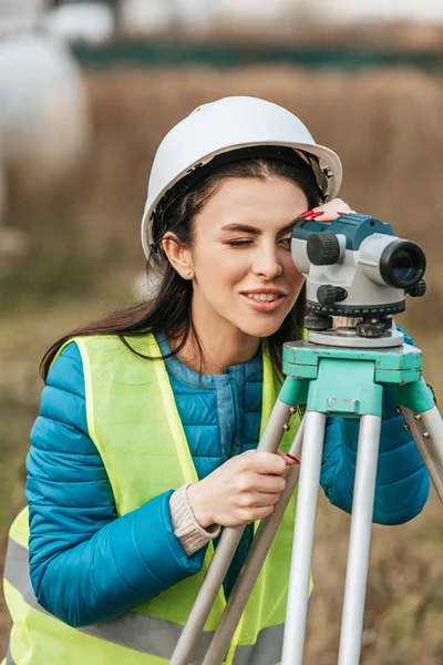 Atractivo topógrafo sonriente que trabaja con nivel digital - foto de stock