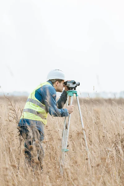 Surveyor with digital level measuring field — Stock Photo